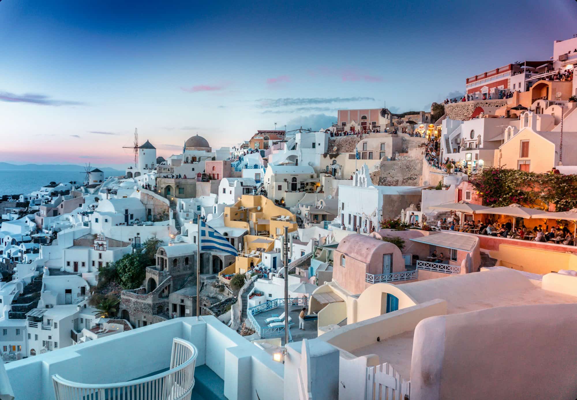 Whitewashed cliffside village glowing at dusk over the Aegean Sea