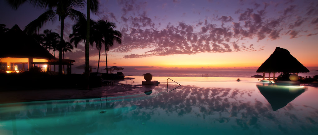 Sunset over a luxury hotel infinity pool overlooking the ocean